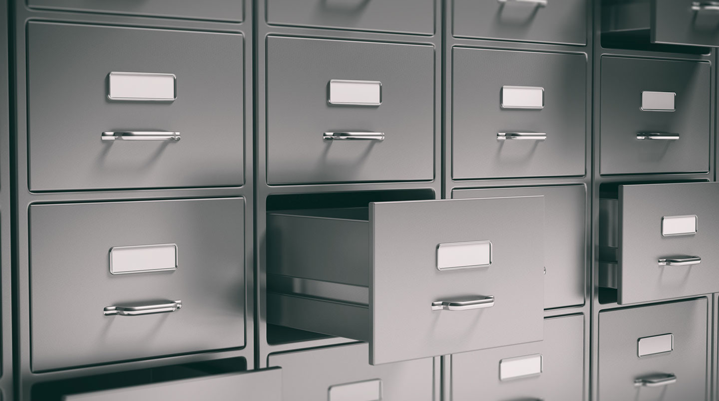 Une armoire forte modulaire métallique ouverte montrant plusieurs tiroirs et étagères amovibles dans une salle d'archives professionnelle éclairée par néon indirect